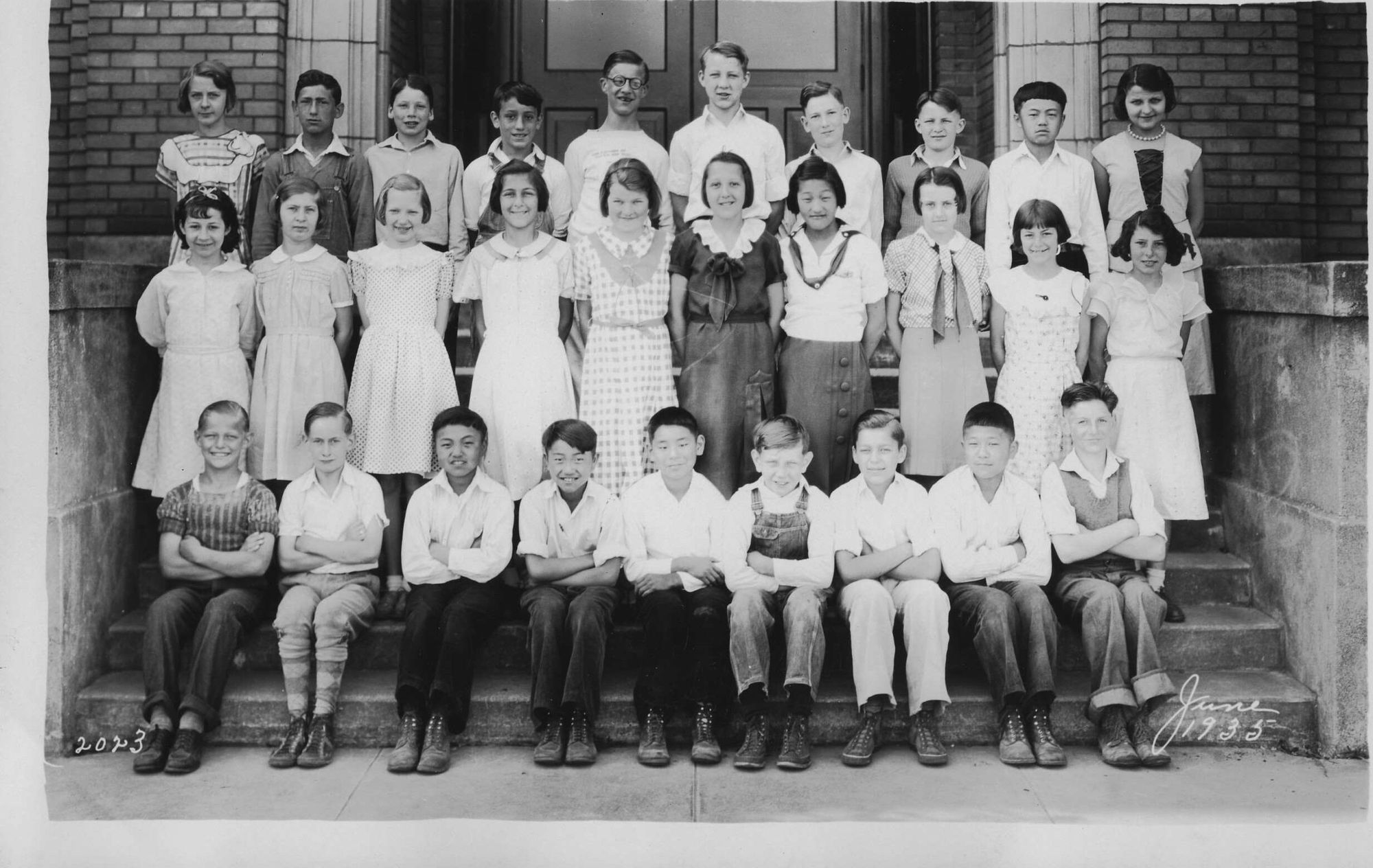 Class portrait, June 1935: boys seated on the bottom step, girls standing behind.