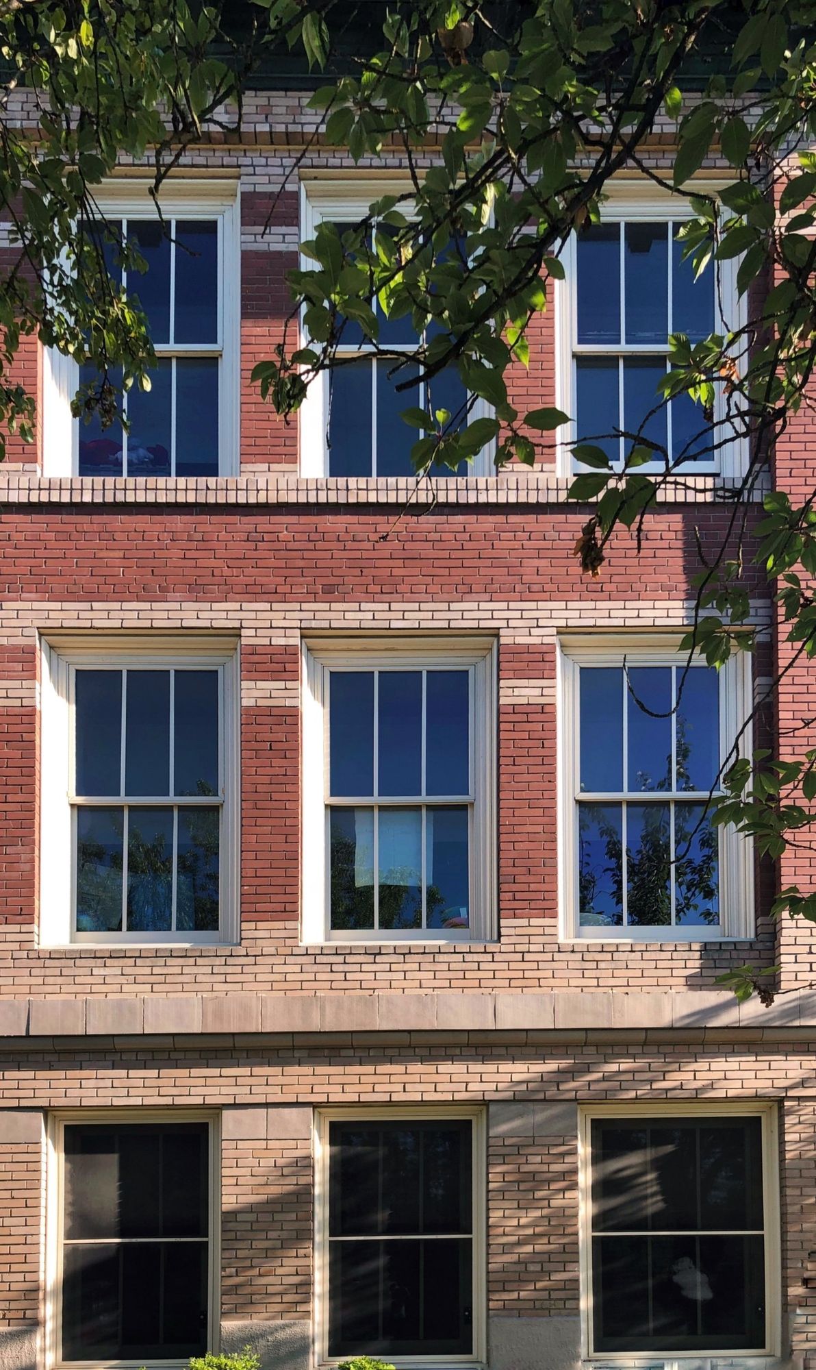Close view of the red and buff brick north facade with tall sash windows.